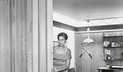 In the 1950s Pella released the wood folding door, as seen in this historical image of a woman operating the door.