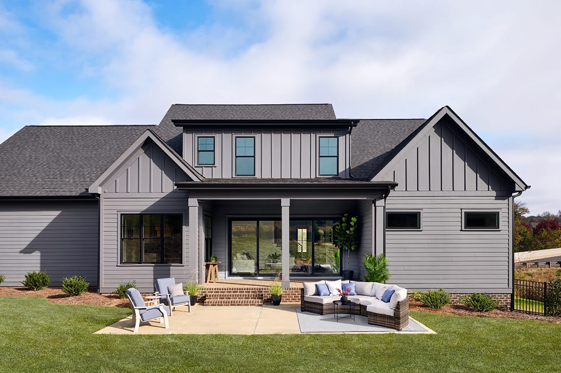 Large glass patio doors on a gray modern home with outdoor seating and a covered porch.