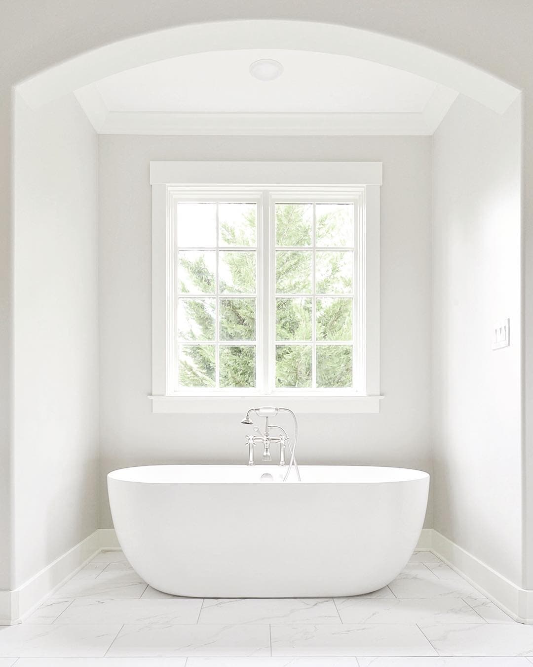 Casement Window Brings Touch Of Elegance To White Bathroom White on white bathroom with large casement window over freestanding tub