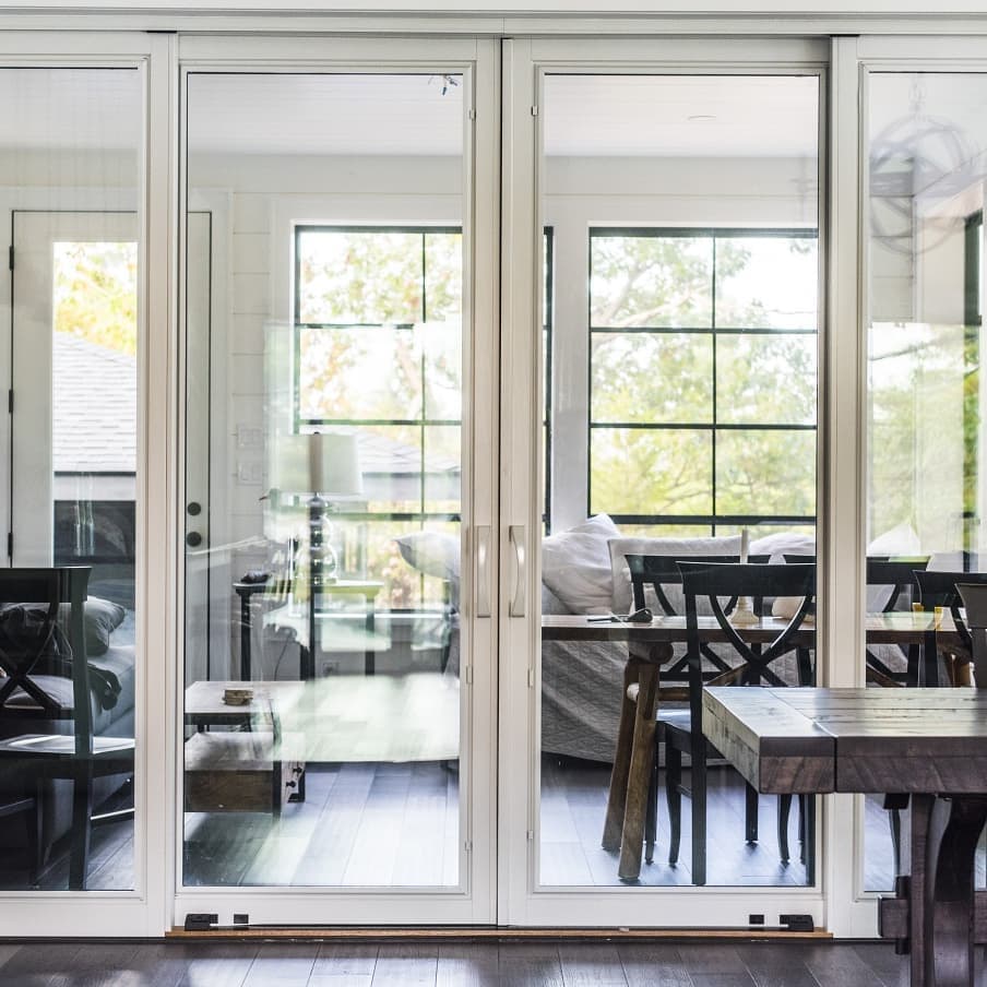 Patio Doors' Minimalist Design Complements Modern Style Sliding patio door with minimal white frame and large expanse of glass separates dining room from backyard
