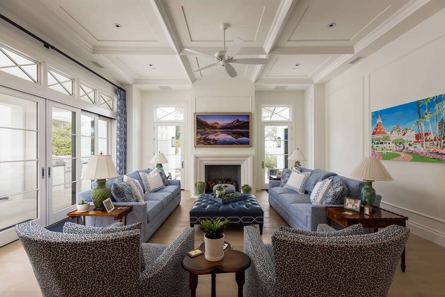 A white living room with blue couches features multi-slide patio doors on one wall with custom grid transom windows above.
