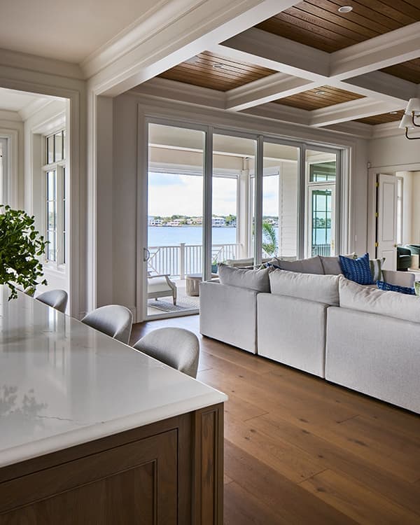 the interior of an open concept home with a large sliding patio door that opens to a lake view and patio.