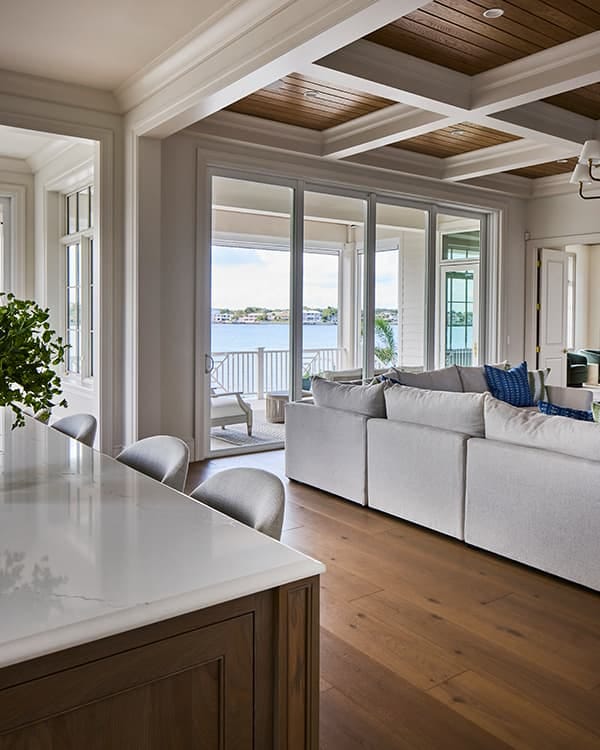 the interior of an open concept home with a large sliding patio door that opens to a lake view and patio.