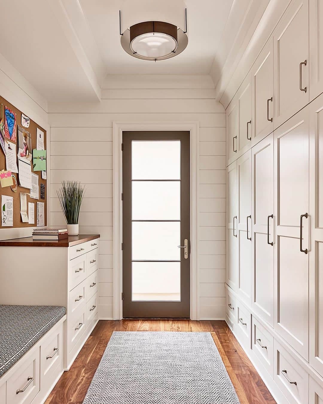 Hinged Glass Patio Door Beautifully Contrasts White Mudroom contemporary style mudroom with a wall of white cabinets leading to hinged glass patio door