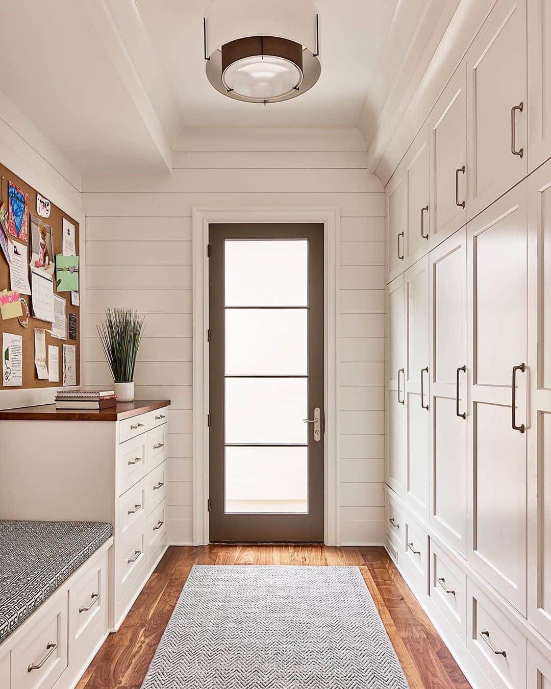 Hinged Glass Patio Door Beautifully Contrasts White Mudroom contemporary style mudroom with a wall of white cabinets leading to hinged glass patio door