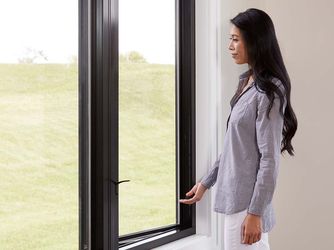 Black‑framed casement window in a bright interior space with a clear outdoor view.