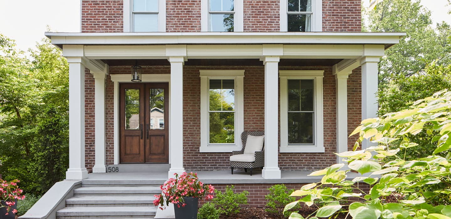 two-story brick home with a two-panel wood entry door