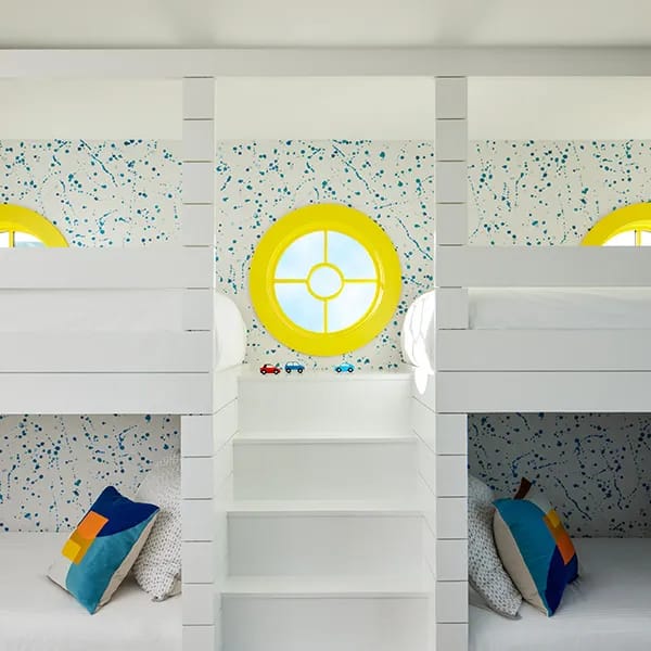 White bunk beds with round yellow windows featuring grilles in a playful kids' room.
