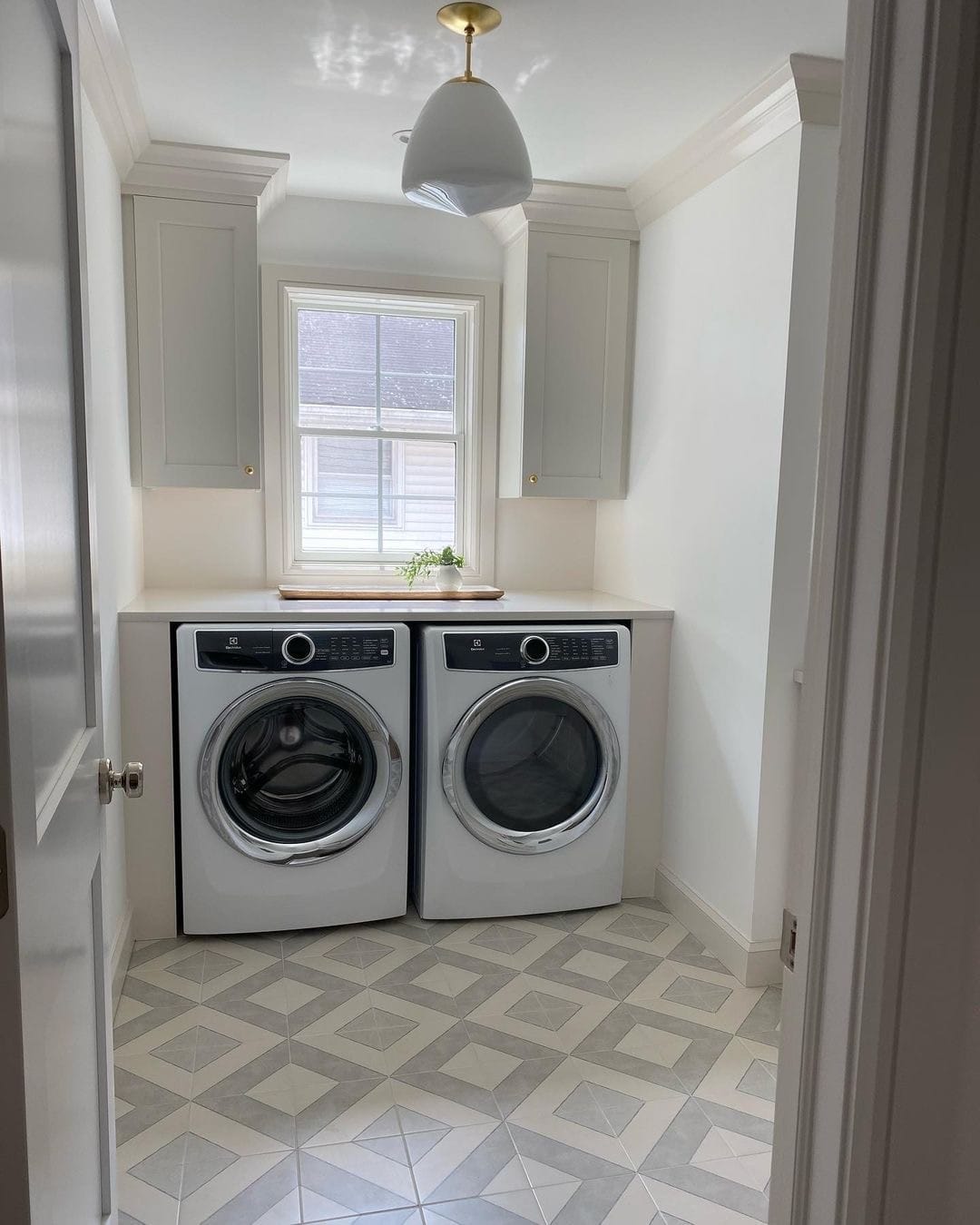 A laundry room window above washer and dryer invites light into the space.