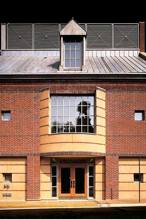 A close view of a large picture window with traditional grilles, framed by decorative brick.