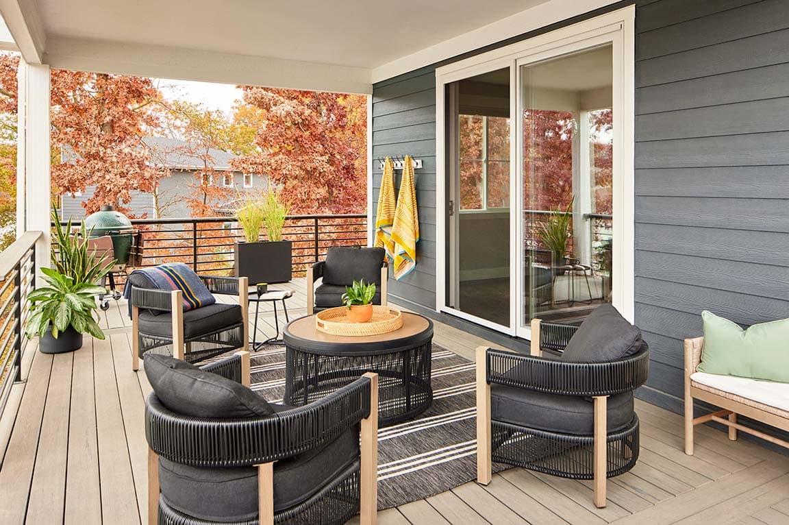 black patio furniture on an outdoor back patio with a white fiberglass sliding patio door to enter the home interior.