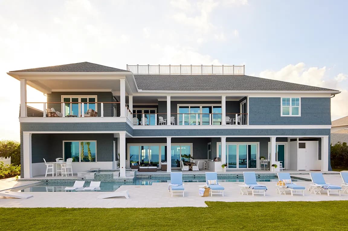 Luxury two-story blue coastal house with swimming pool, upper balcony and sun loungers