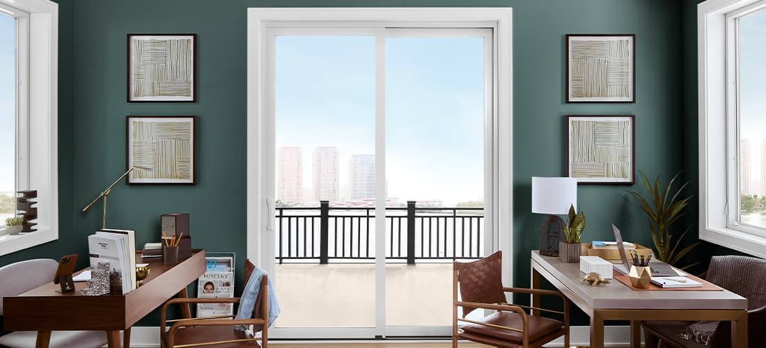 white sliding door in green office space with city view and two wooden desks