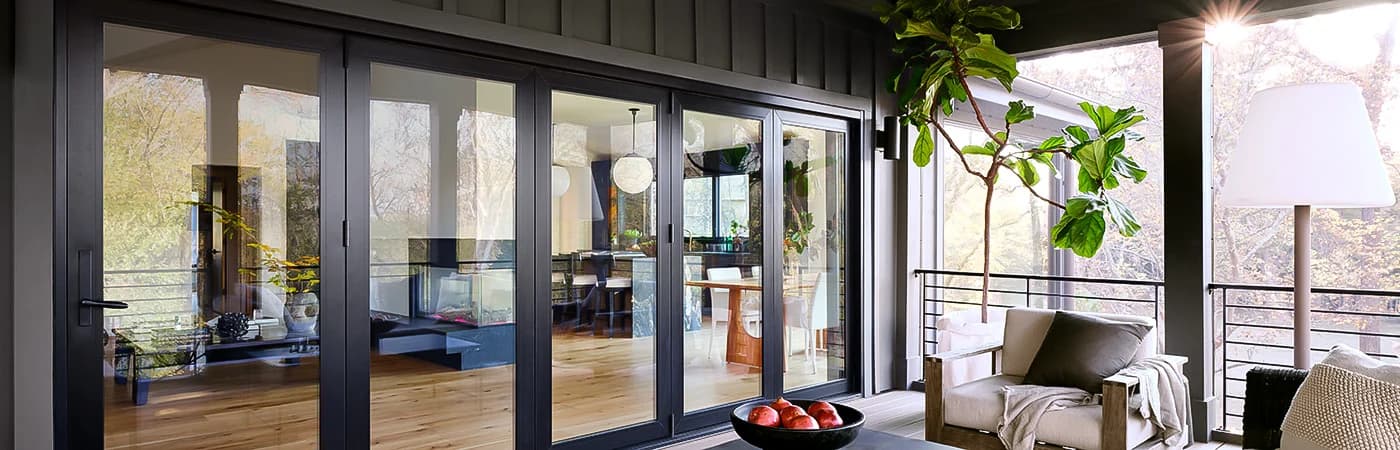 Quality black-framed sliding glass doors open to a modern living space with plants and natural light.