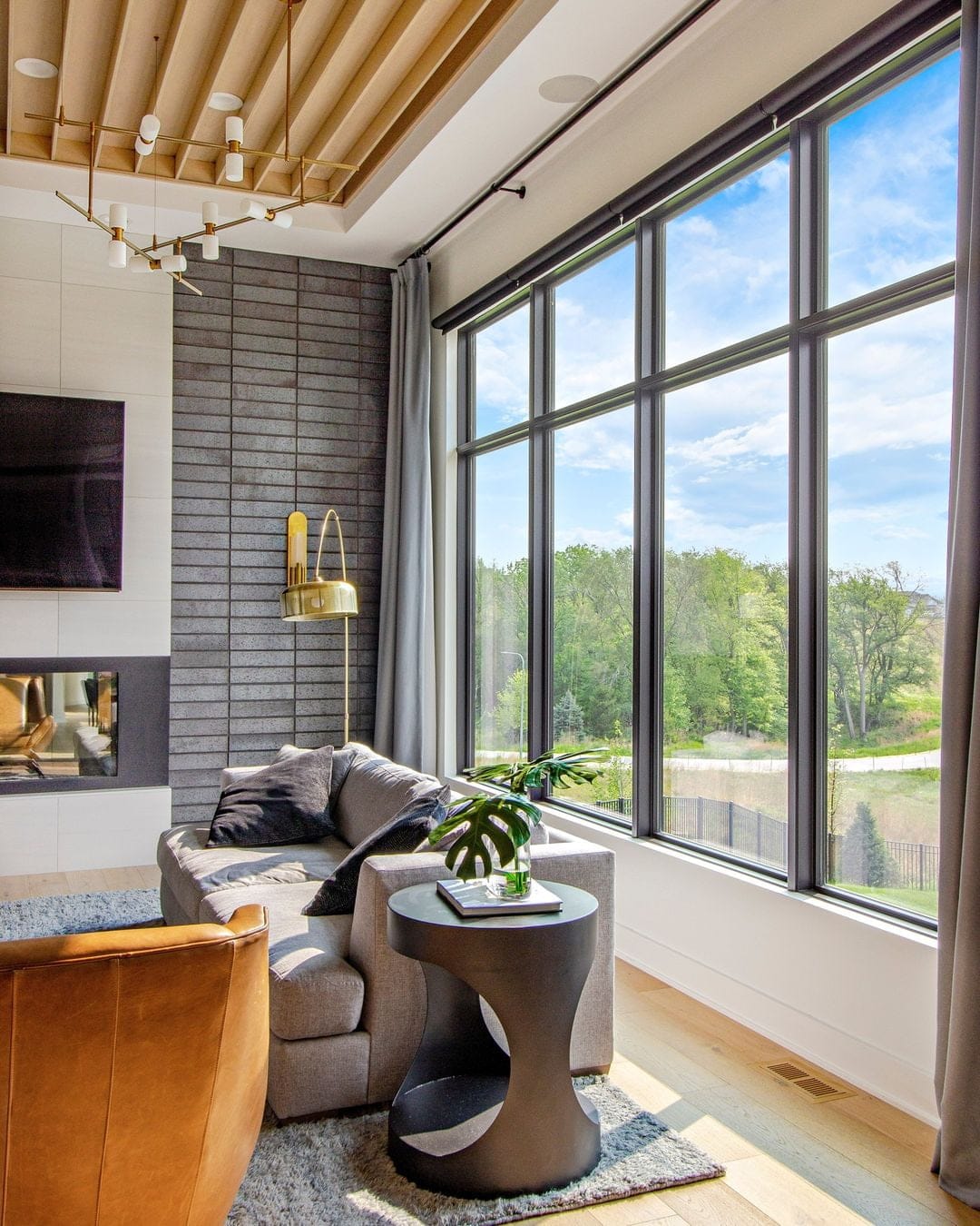 Black picture windows are behind a gray couch in a modern living room.