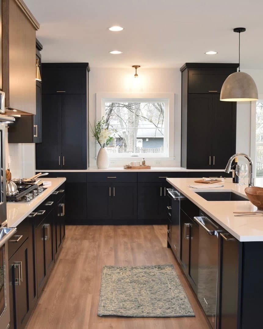 A white window is nestled between two dark cabinet towers in a traditional kitchen.