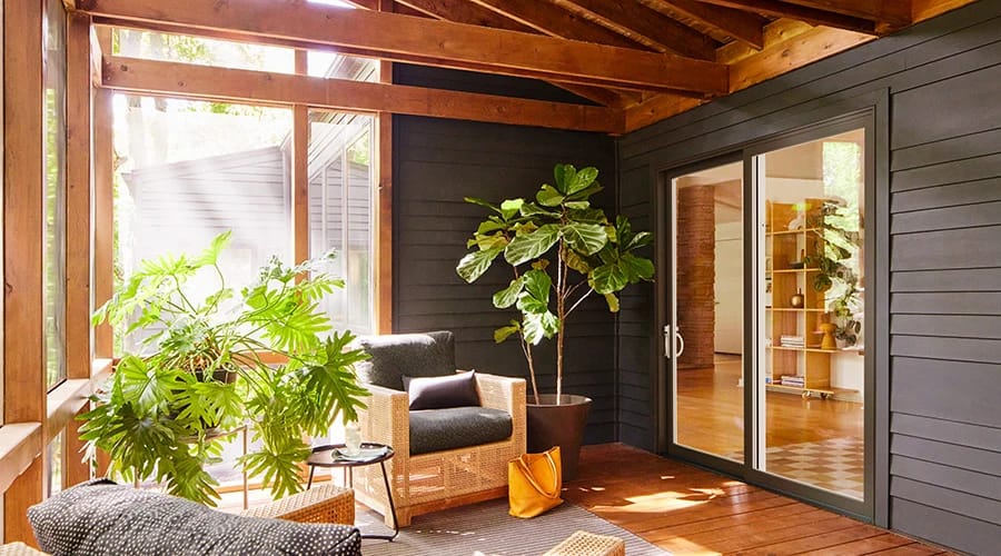 Houston Project features a cozy enclosed patio with dark siding and sliding glass doors.