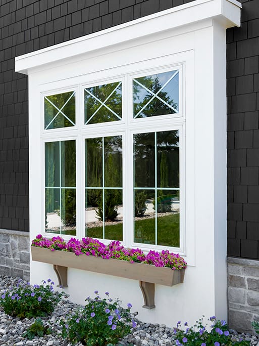 Whit diamond grille casement window on cottage-style home.
