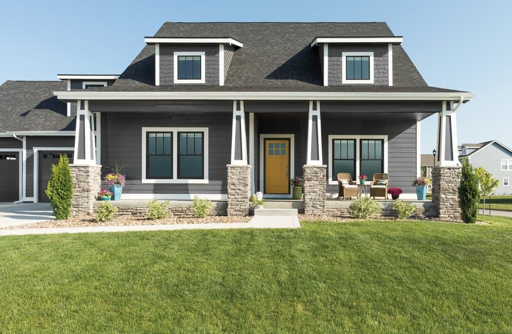 Black Vinyl Windows Endure The Elements Beautifully Gray cape cod style home with black windows, white trim, and a yellow front door