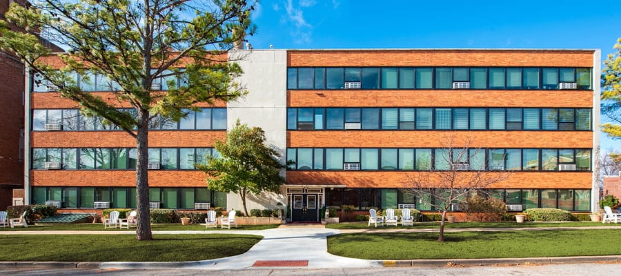 Four-story building with black commercial windows with white blinds