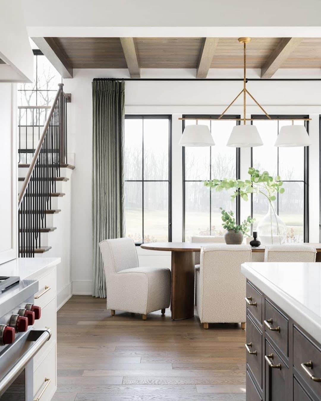 Three black windows with simple grilles stand side-by-side behind a dining table.