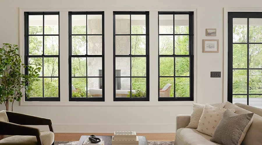 A modern living room with glass sliding doors, wood and fabric materials, and a woman opening the door.