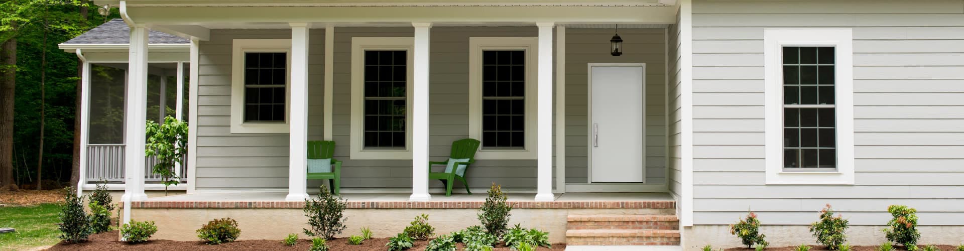 exterior of a single-story gray home with a white steel entry door on the left side of the porch