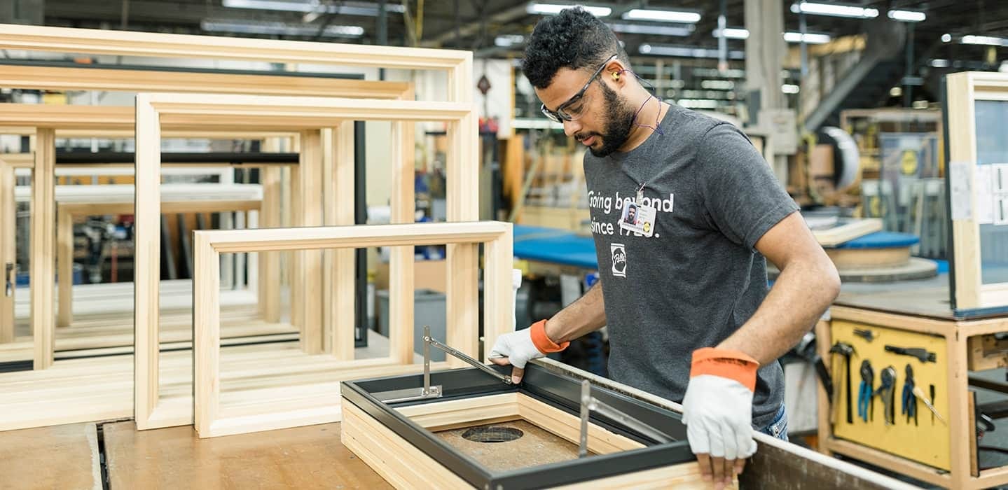 A Pella manufacturing team member is working on a wood awning window, testing the arms.