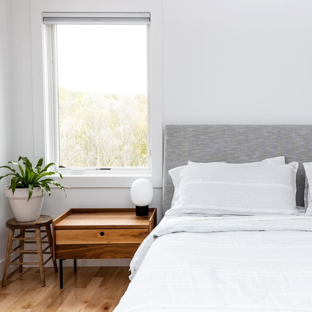 Casement Window For A Light & Bright Contemporary Bedroom light and bright minimalist style bedroom with large casement window, nightstand, and plant