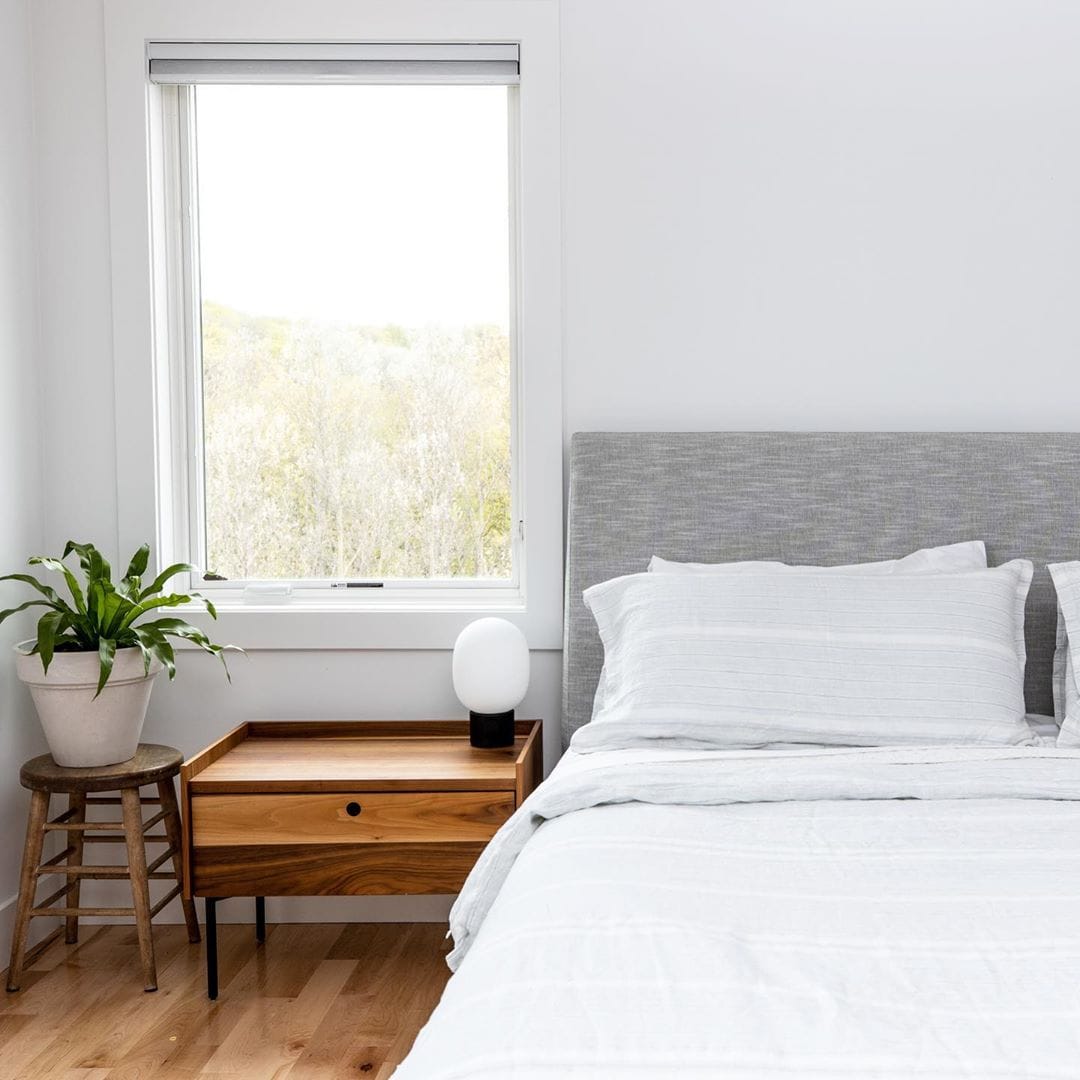 Casement Window For A Light & Bright Contemporary Bedroom light and bright minimalist style bedroom with large casement window, nightstand, and plant