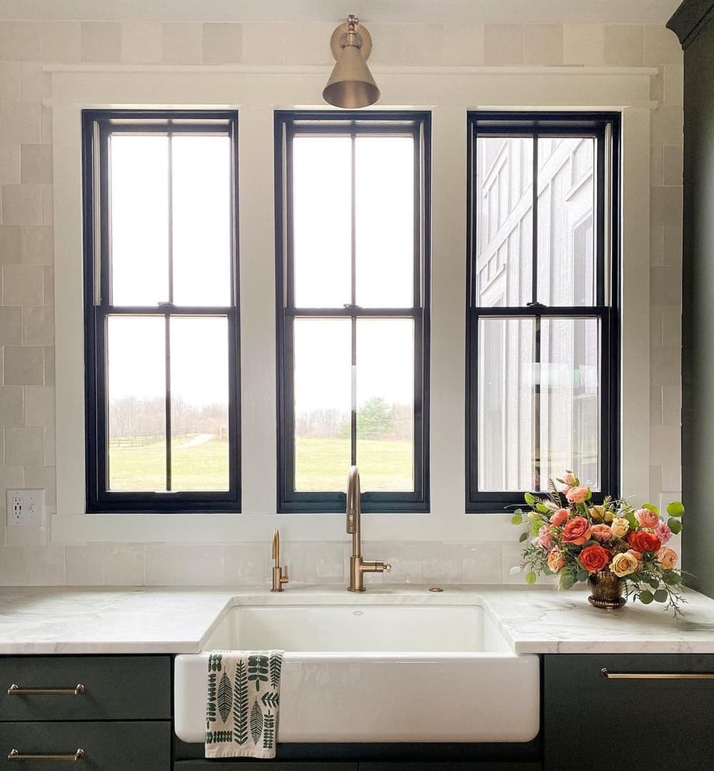 Three black kitchen windows sit above a white apron-style sink.