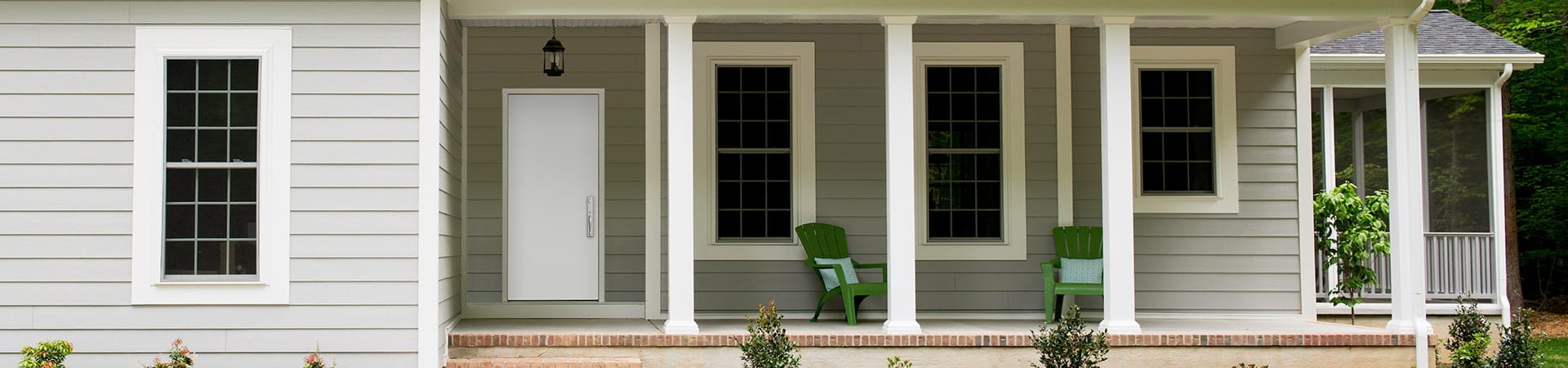 gray single-story home with a deck outside the entry door in white