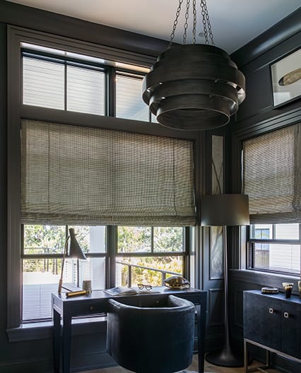 Dimly lit office space featuring multiple opened double-hung windows.