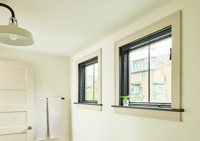 A contemporary table sits in front of three floor-to-ceiling casement windows