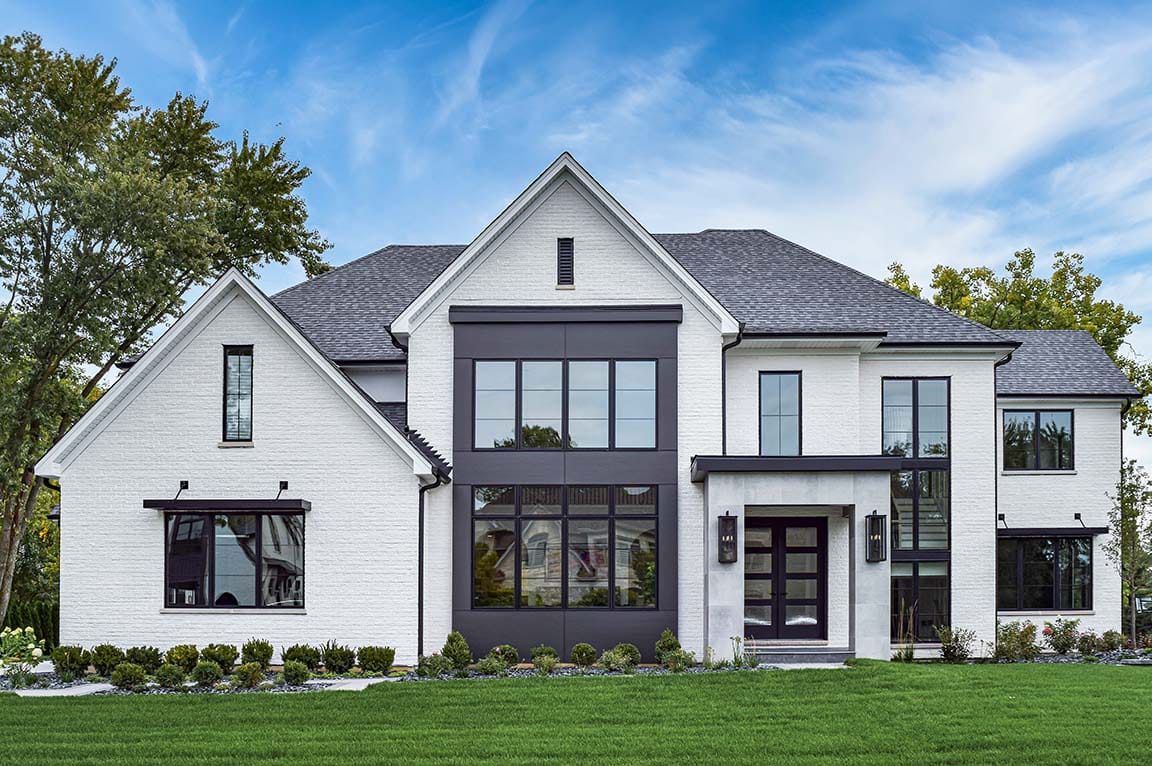 Modern white brick home with black-framed windows and symmetrical front elevation.