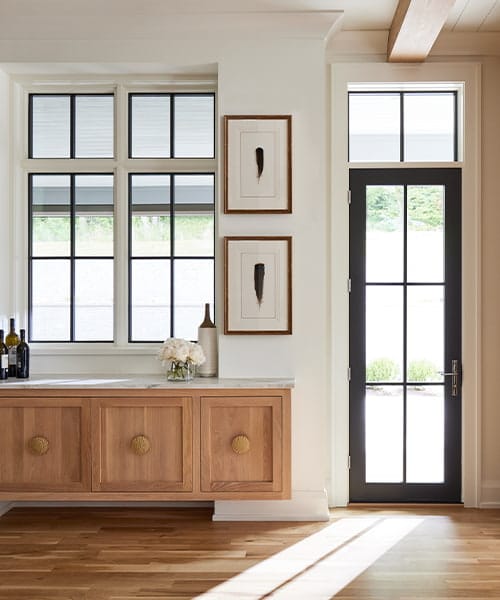 Home entryway with a black hinged door and black windows with transoms