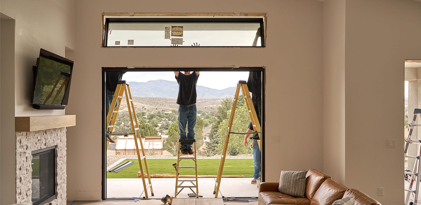Technicians installing a sliding patio door in a living room.