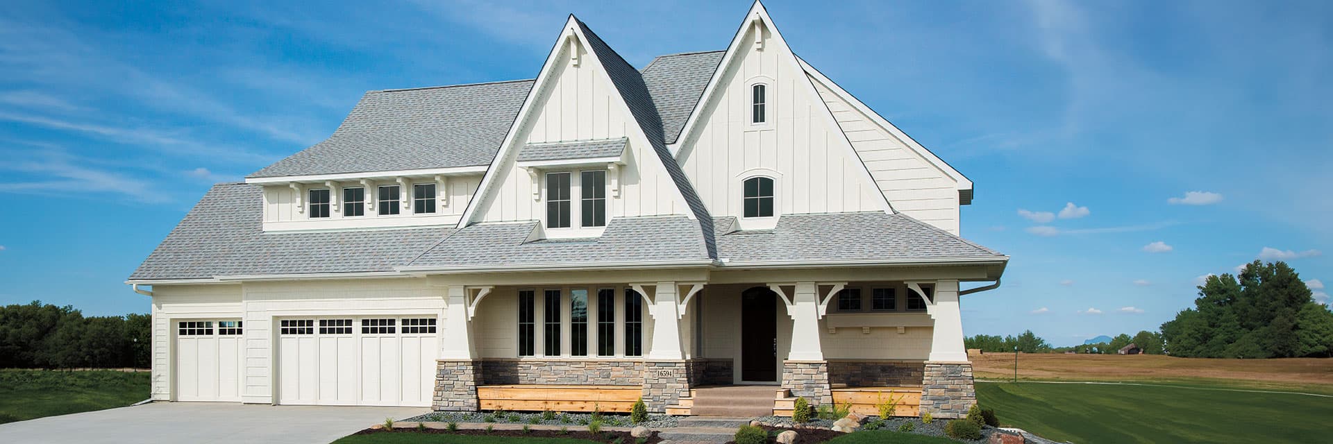 A large white home with an expansive outdoor deck surrounding the entire front of the home.
