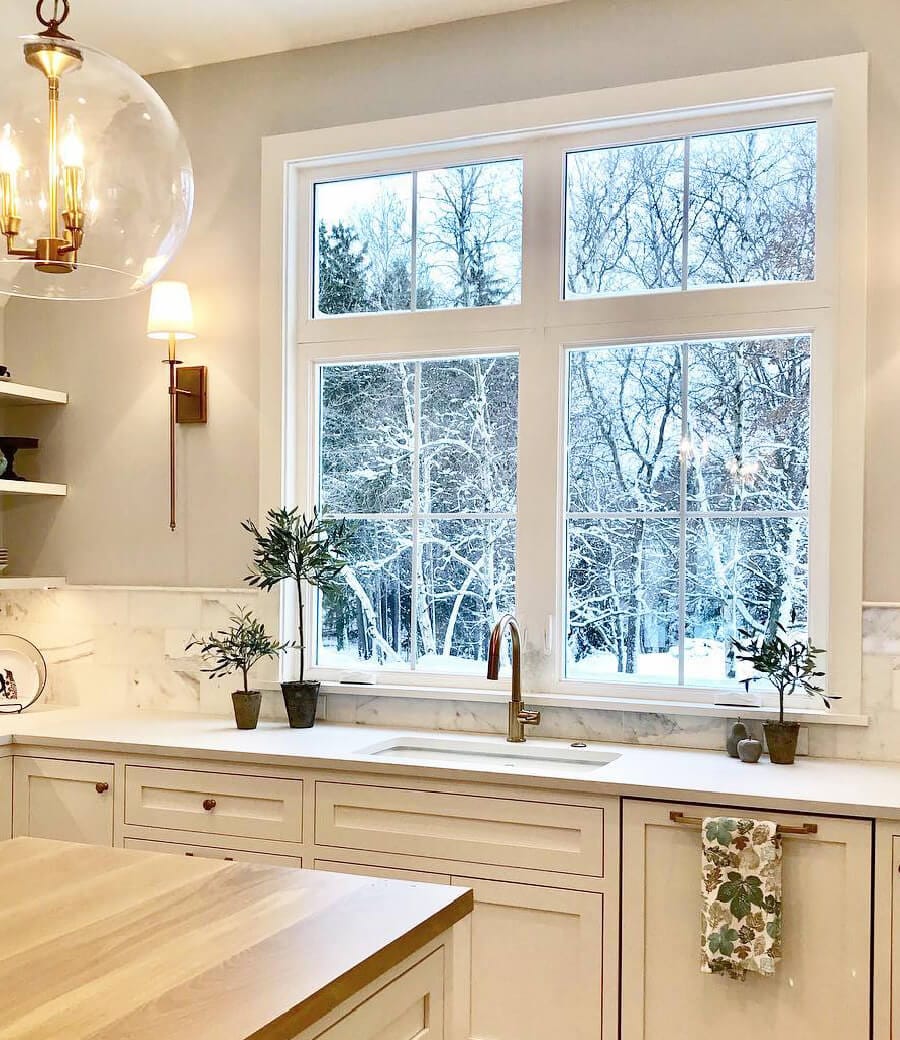 White Casement Windows Brighten Farmhouse Style Kitchen Bright white kitchen illuminated by two casement windows over the sink