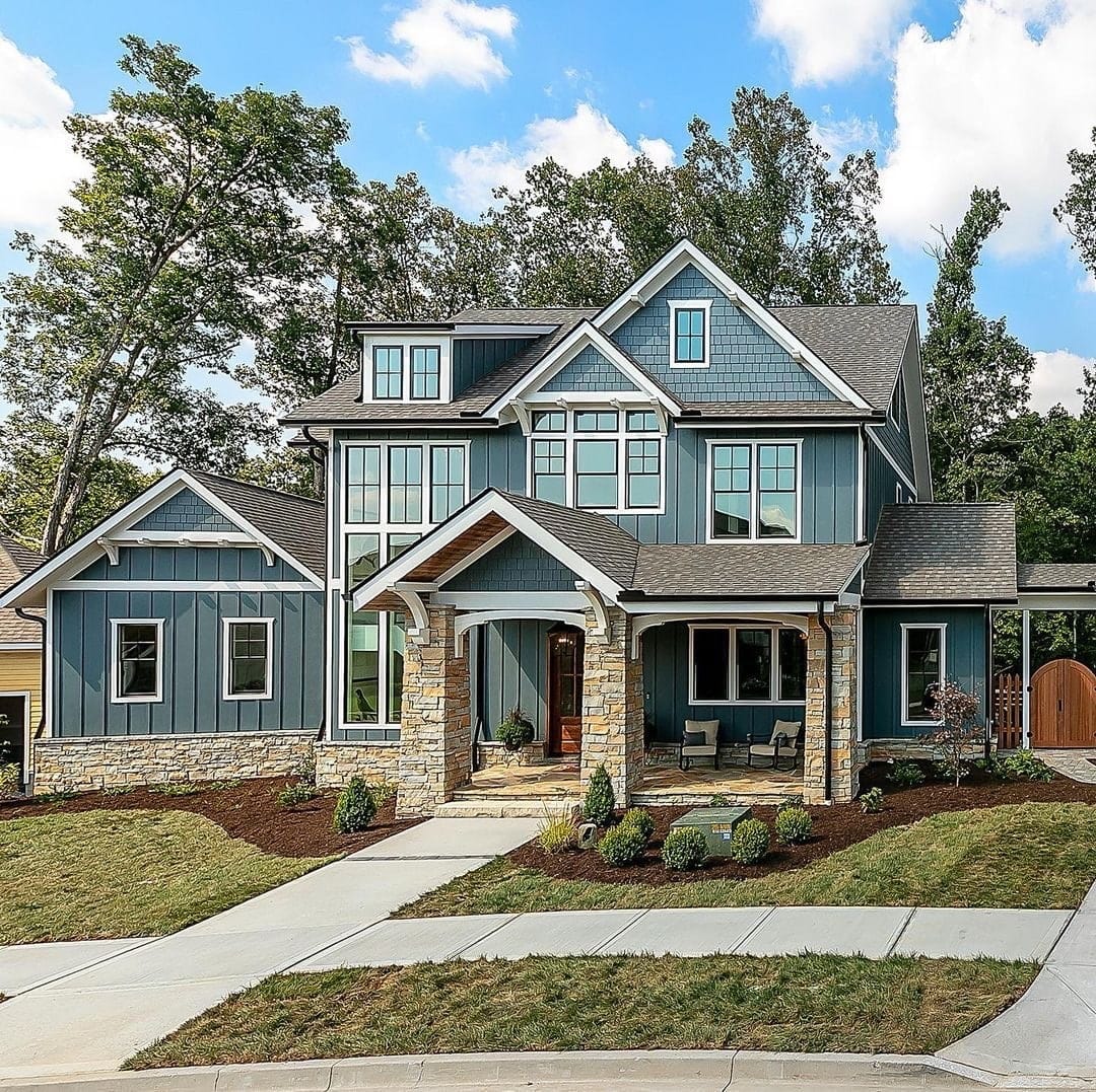 The exterior of a blue house has black windows with white trim.