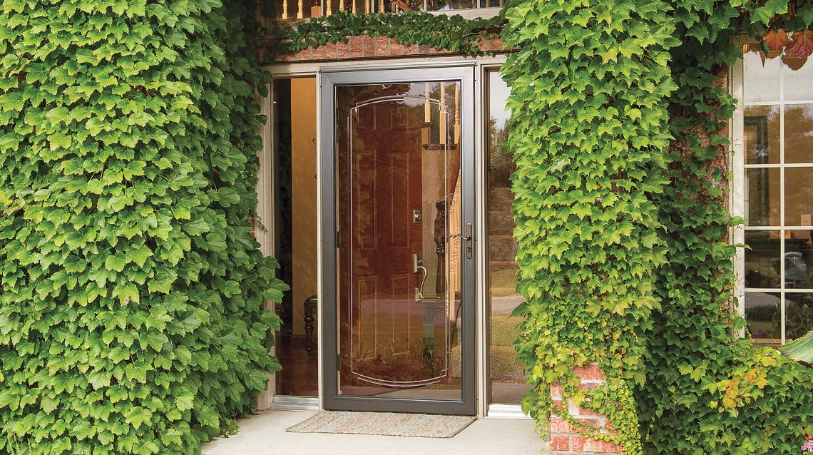 ivy-covered home with a pella storm door over a brown front door