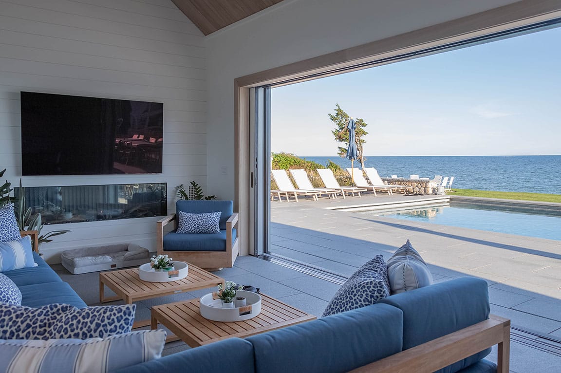 Living room with multi-slide glass doors opening to a pool and ocean view.