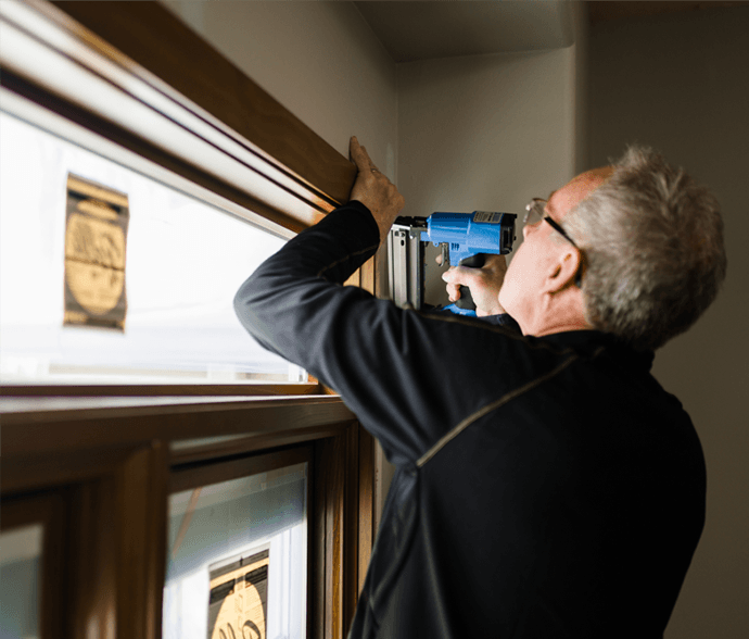 a man installing the transom of a wood window