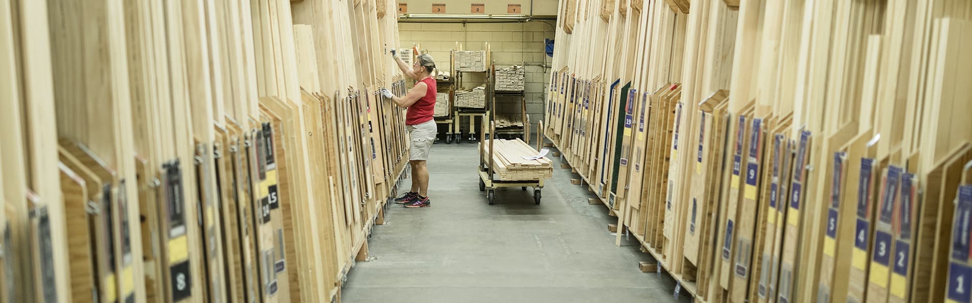 A Pella team member is picking through large wood containers and standing in front of a cart with raw wood on it.