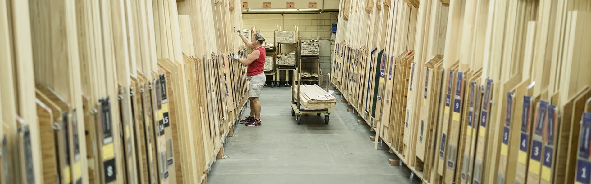 A Pella team member is picking through large wood containers and standing in front of a cart with raw wood on it.