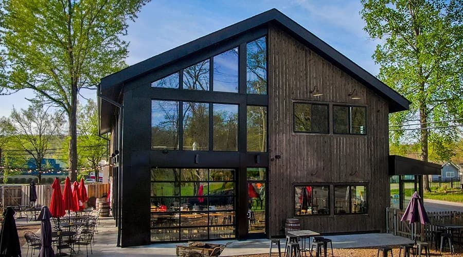 Fiberglass Miamiville Trailyard with dark wood siding, black trim, and expansive modern windows.