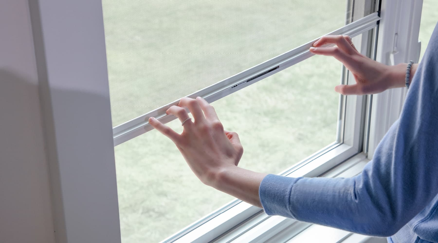 two hands operating a double-hung window