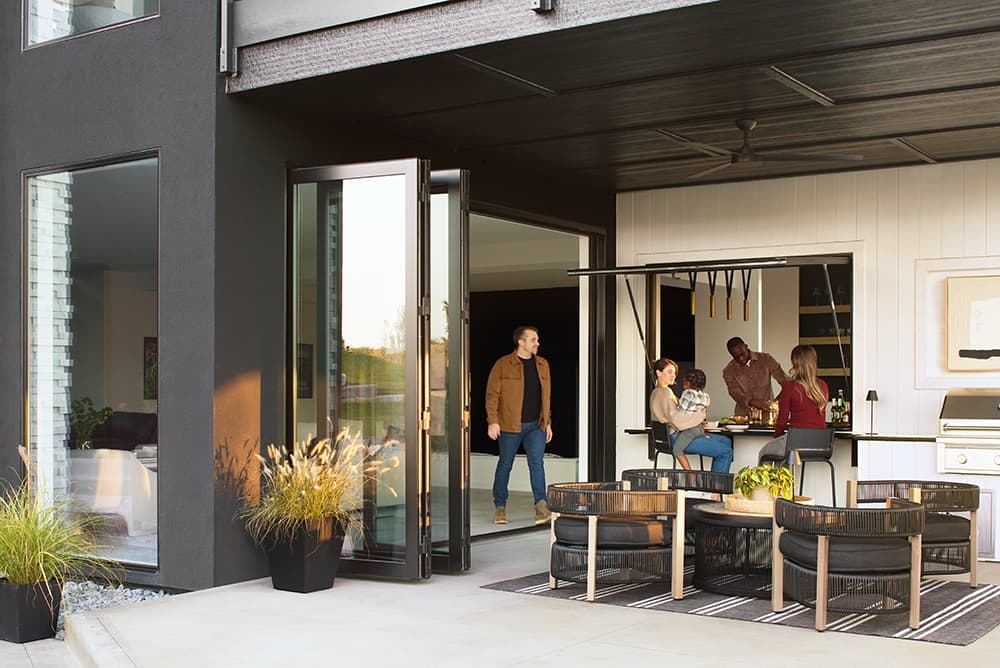 A group of people are enjoying each other's company at a home with a dramatic outdoor patio and a strut awning window.
