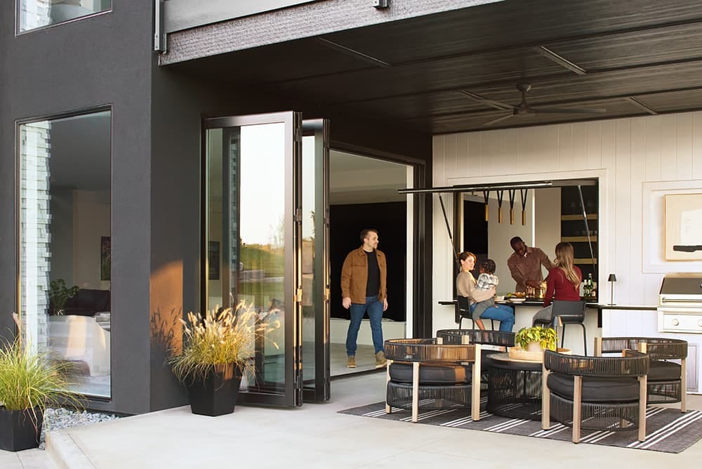 A group of people are enjoying each other's company at a home with a dramatic outdoor patio and a strut awning window.