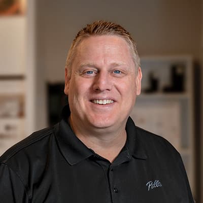 A man named Scott is wearing a black Pella shirt and smiling at the camera lens.